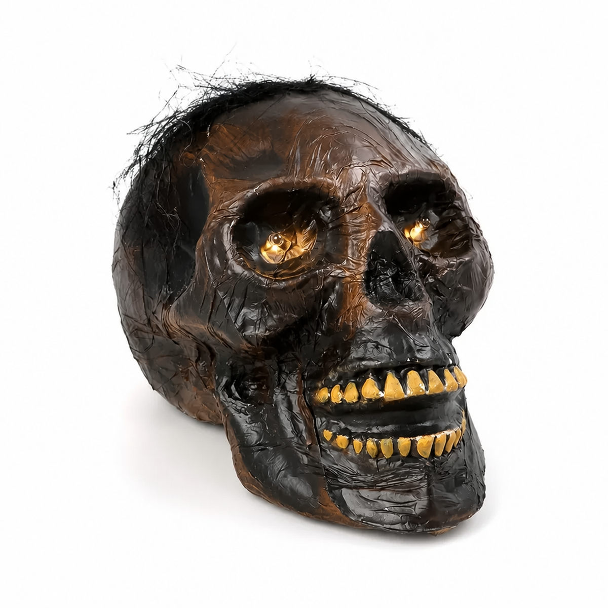 Isolated front angle of light up skull halloween decoration with textured brown skin, golden teeth and glowing eyes.