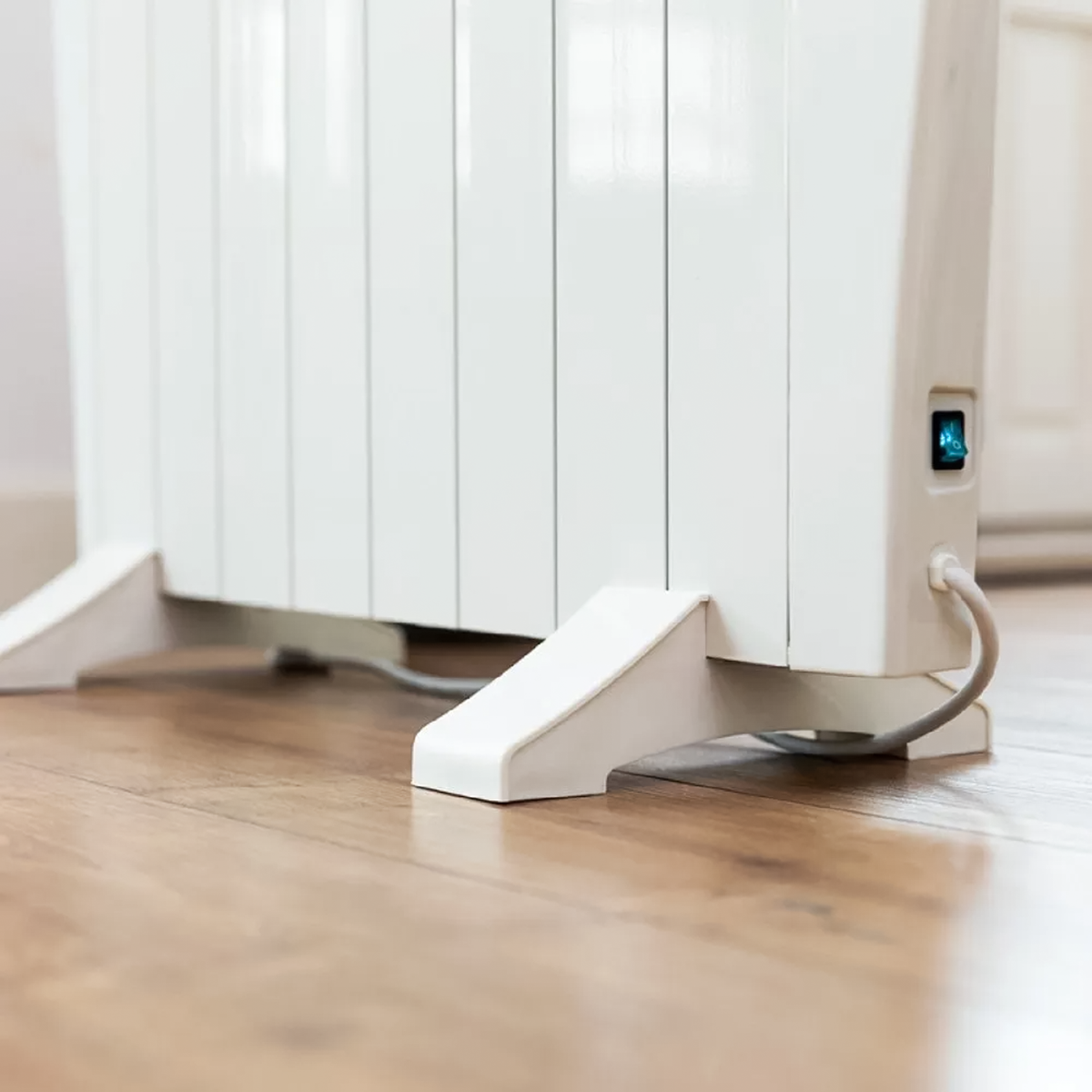 Close up detail of electric thermal radiator support foot, power switch and cable entry.