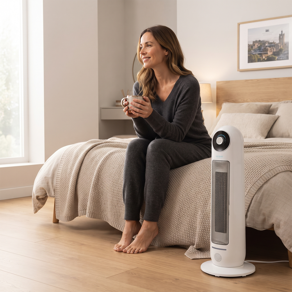 Woman drinking tea on bed with ceramic  tower heater warming the bedroom. 