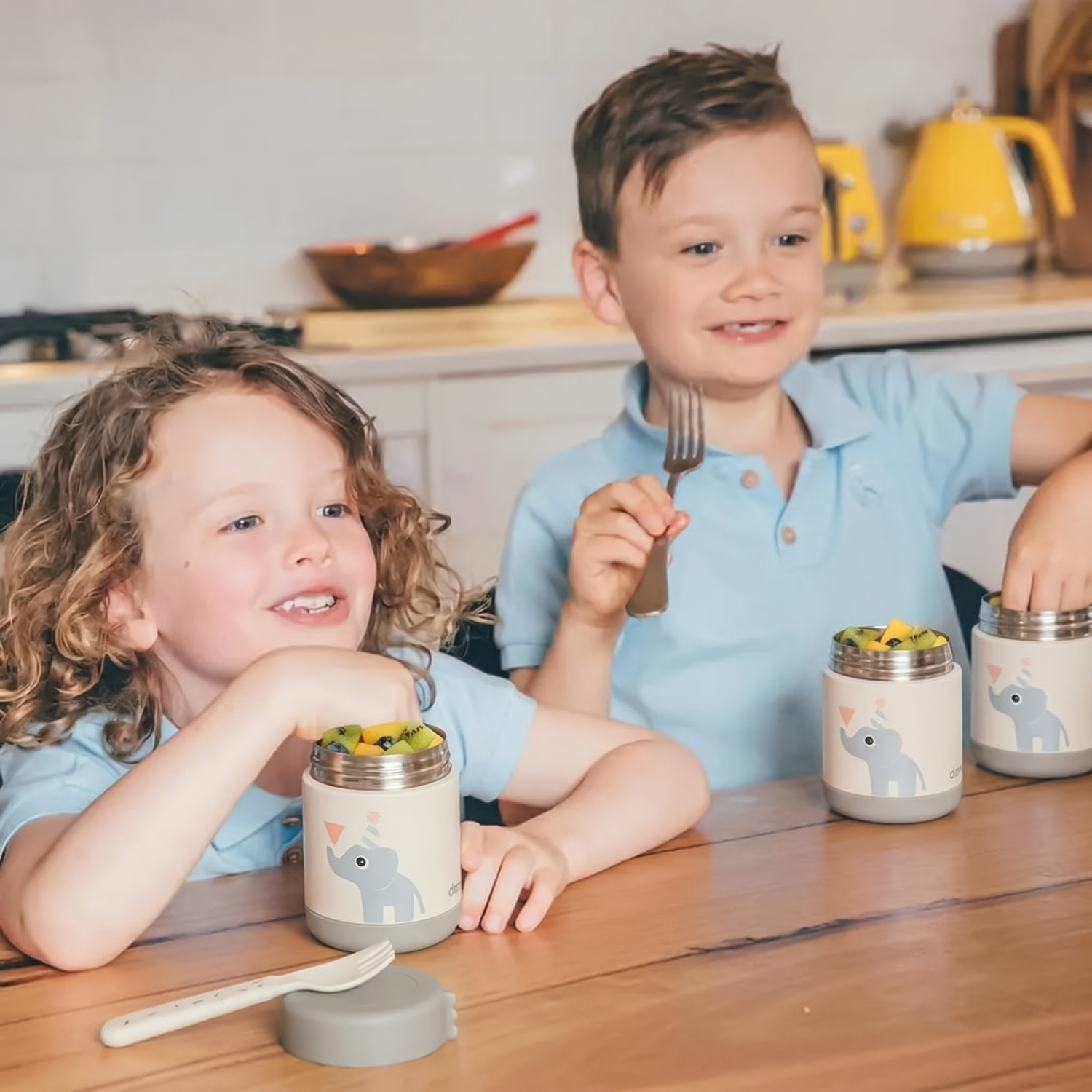 two kids eating from food container 
